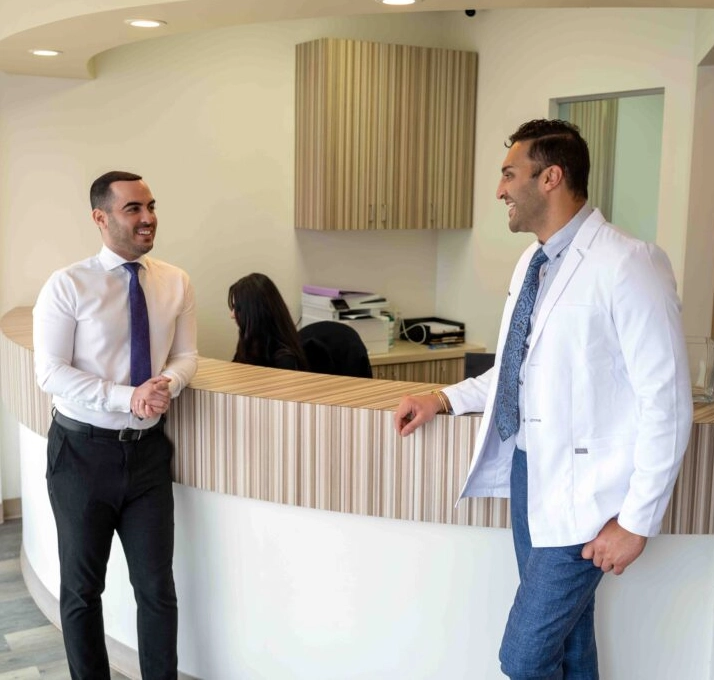 Dr. Arian Noveir standing at his front desk with a man.