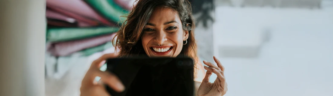 Dentist Northridge CA Dental Checkups A woman looking at her phone smiling.